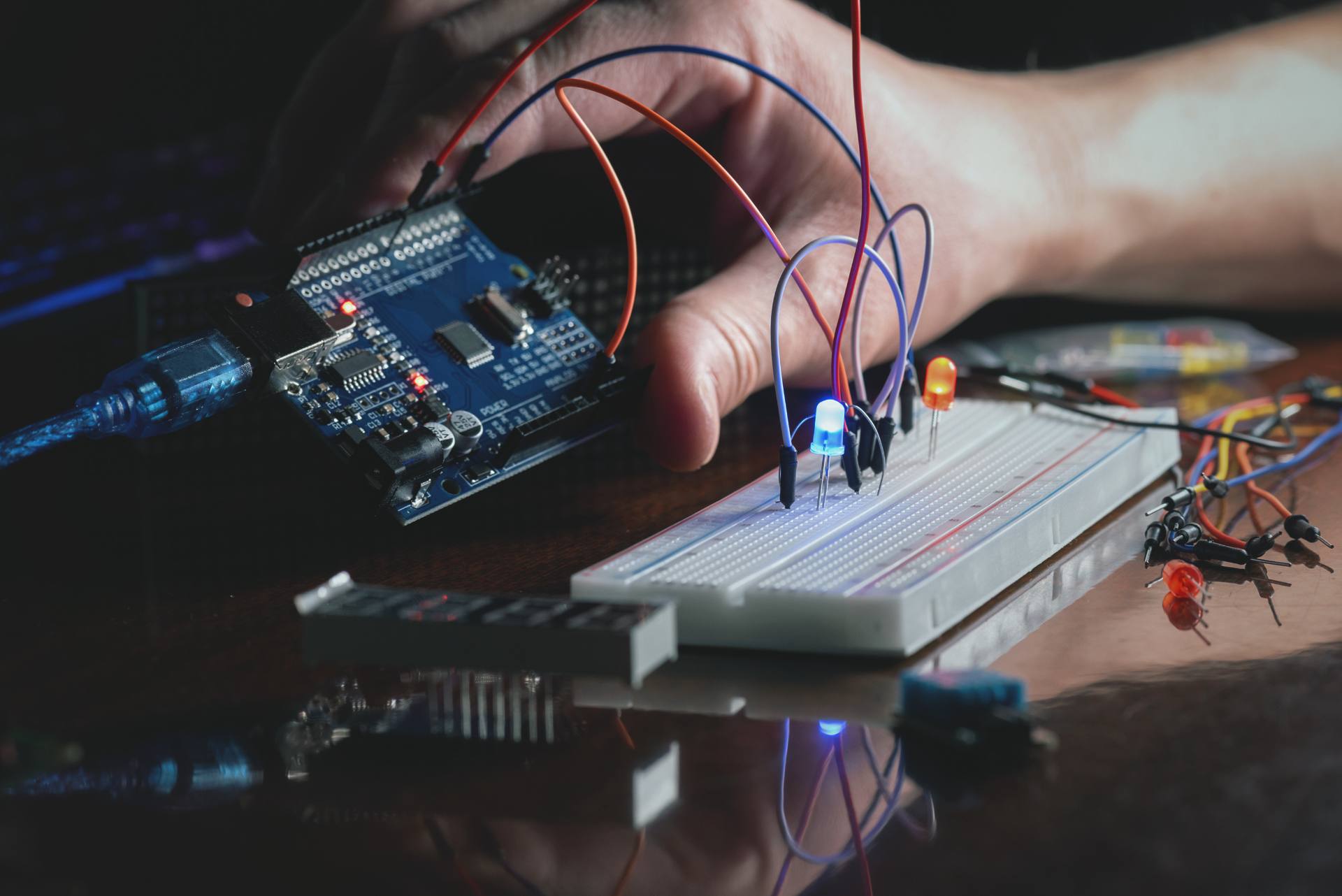 A student wiring LEDs on a breadboard beside an Arduino